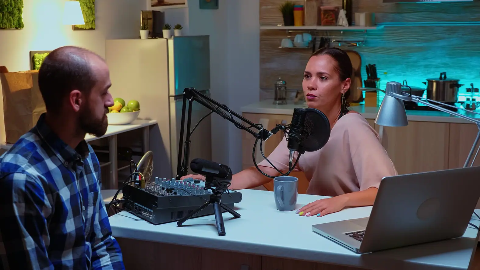 Podcast recording session with two hosts in a modern kitchen setting.